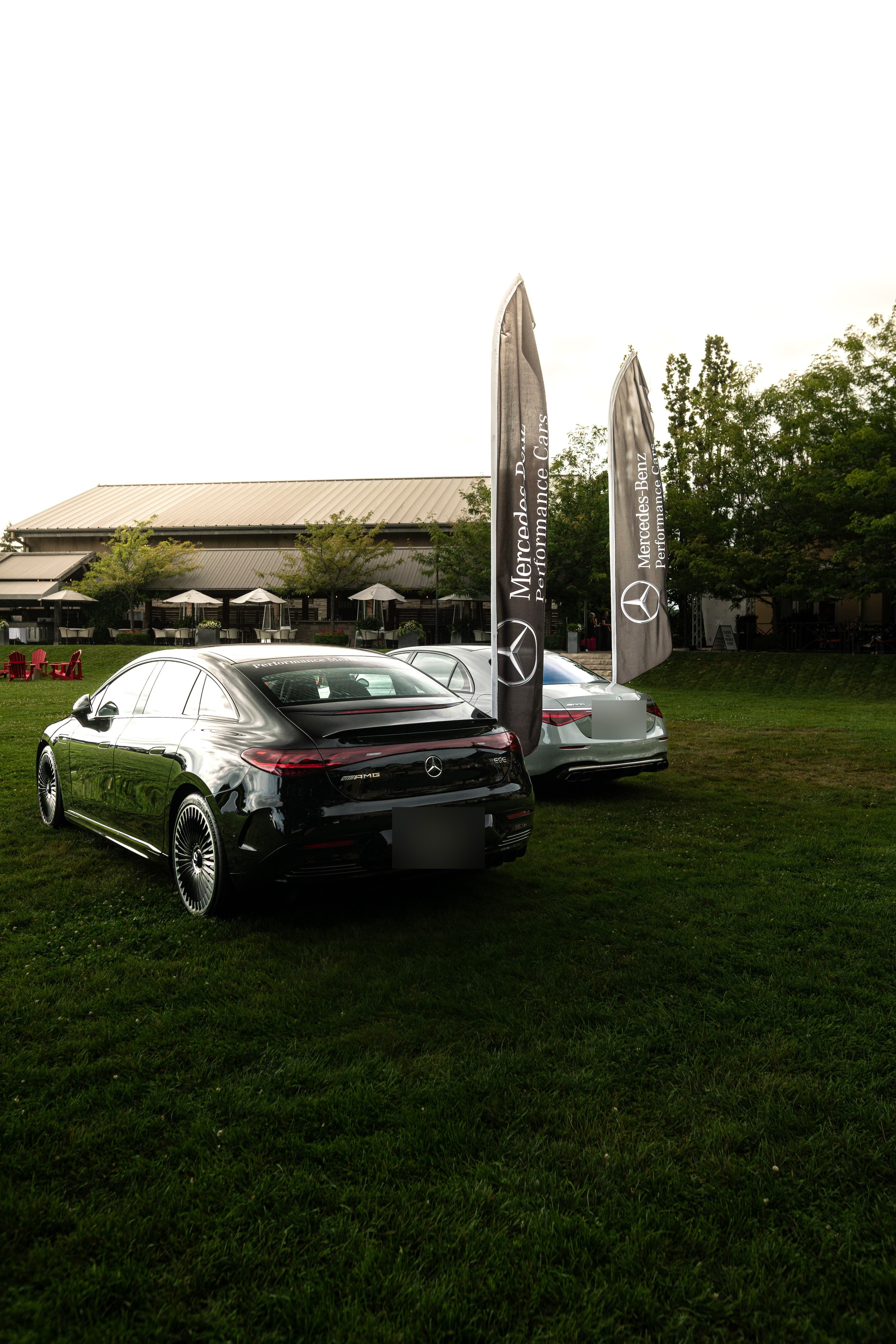 Two Mercedes-AMG sedans parked on winery lawn beside Mercedes-Benz banners