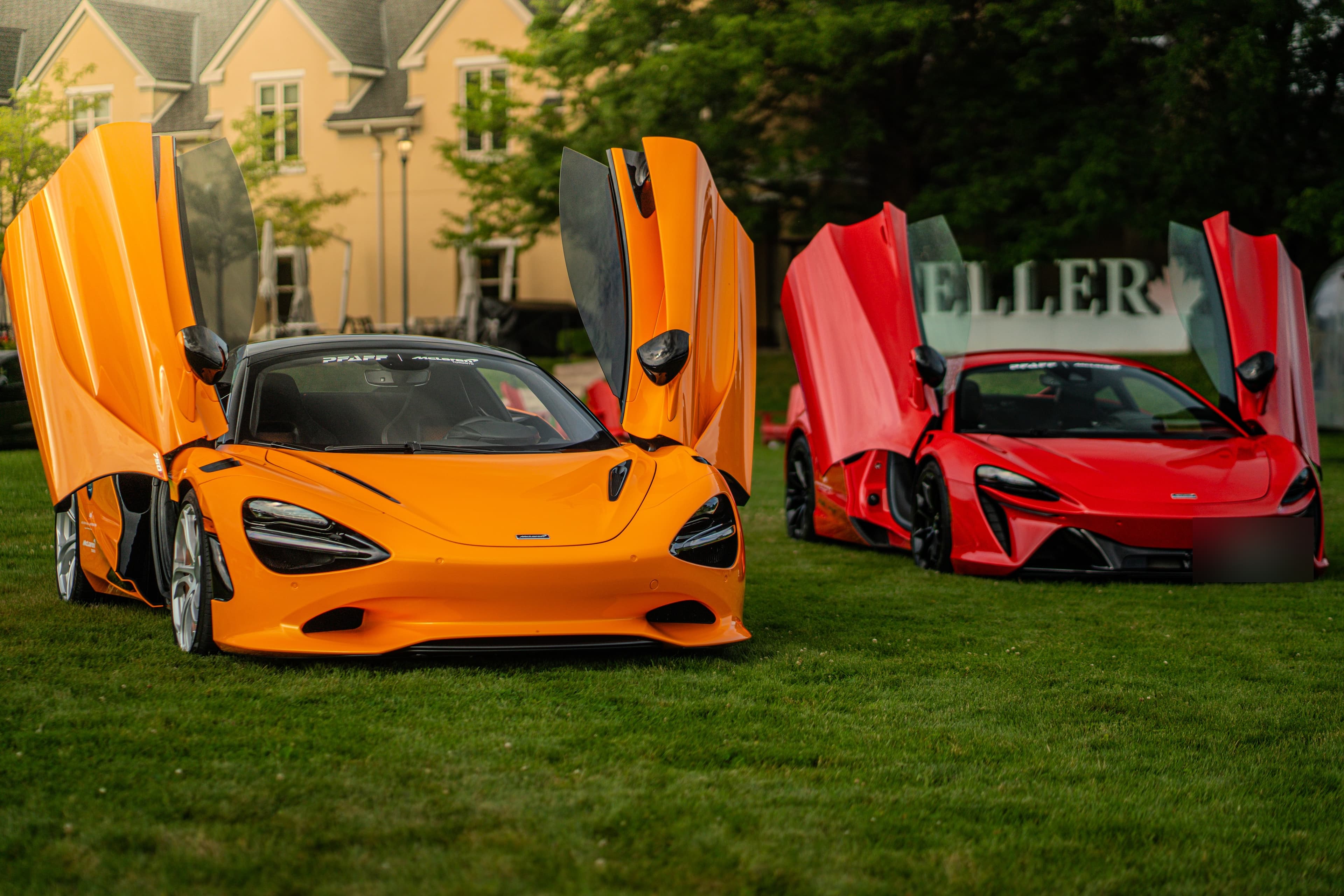 Orange and red McLarens with doors raised on the Peller Estates lawn