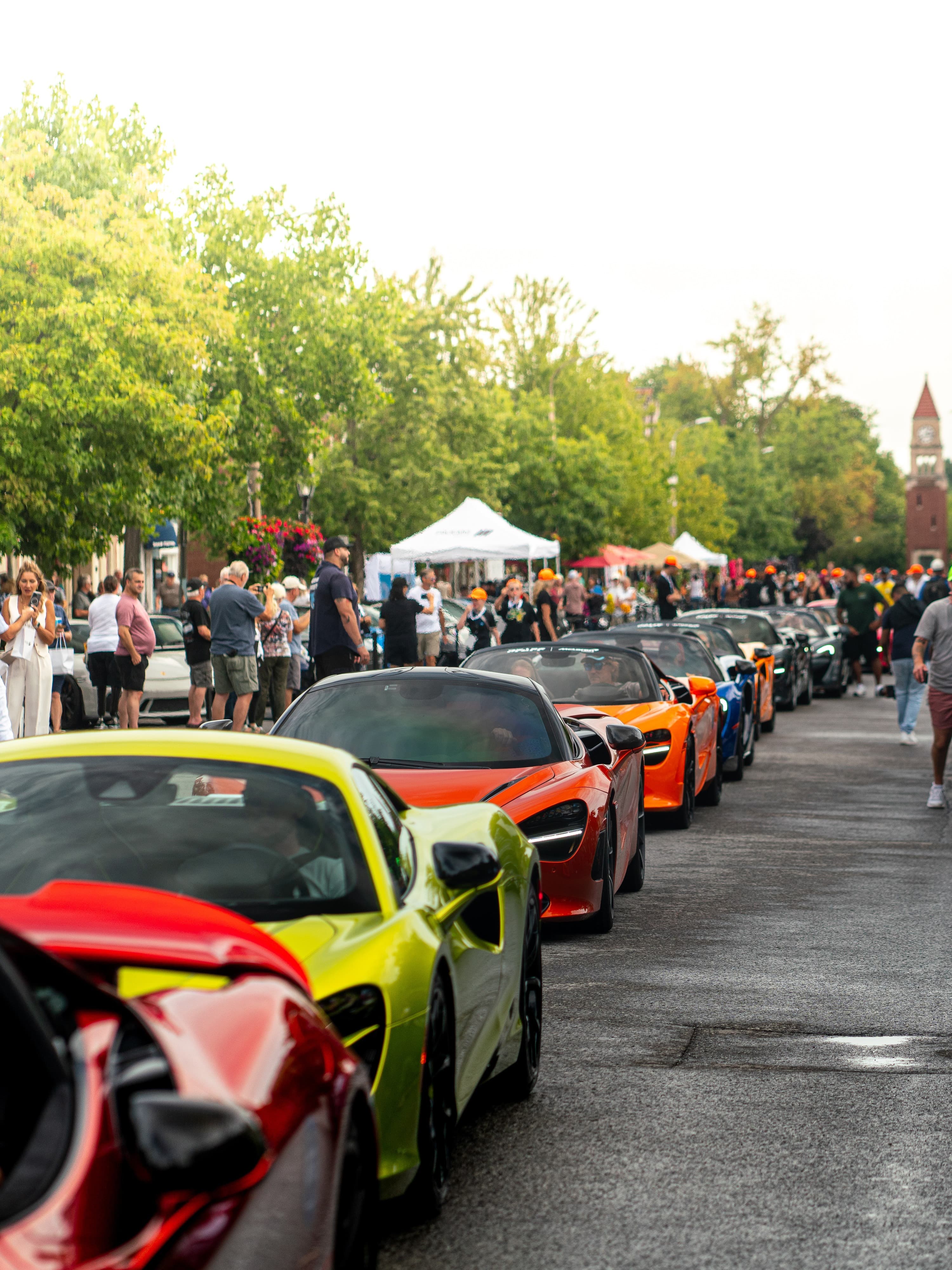 Row of supercars lining Queen Street as crowds watch the parade
