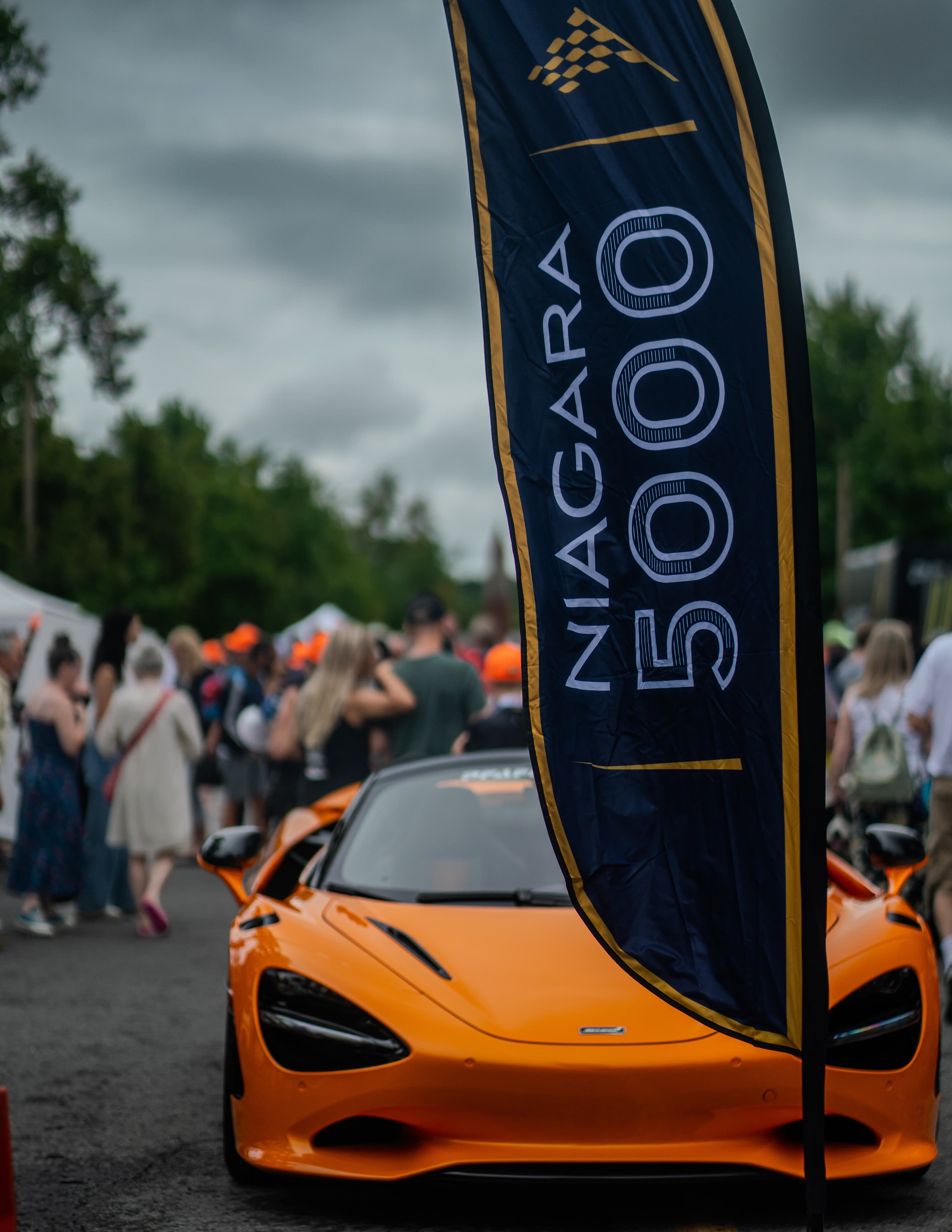 Orange McLaren supercar beside a Niagara 5000 branded feather flag